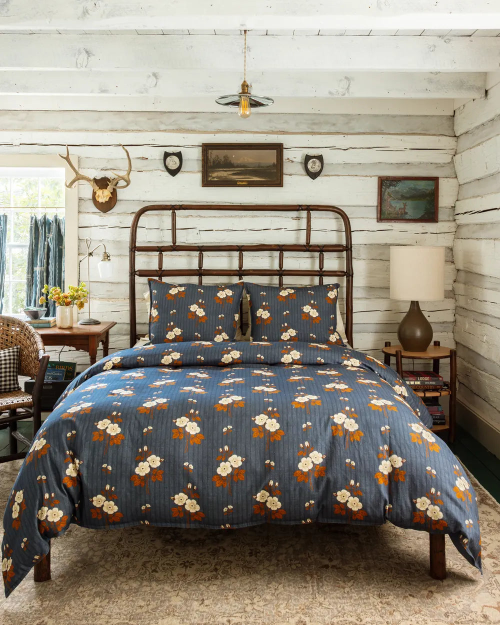 Folk floral duvet cover and shams, cream and rust blossoms on denim blue, on a hickory bed