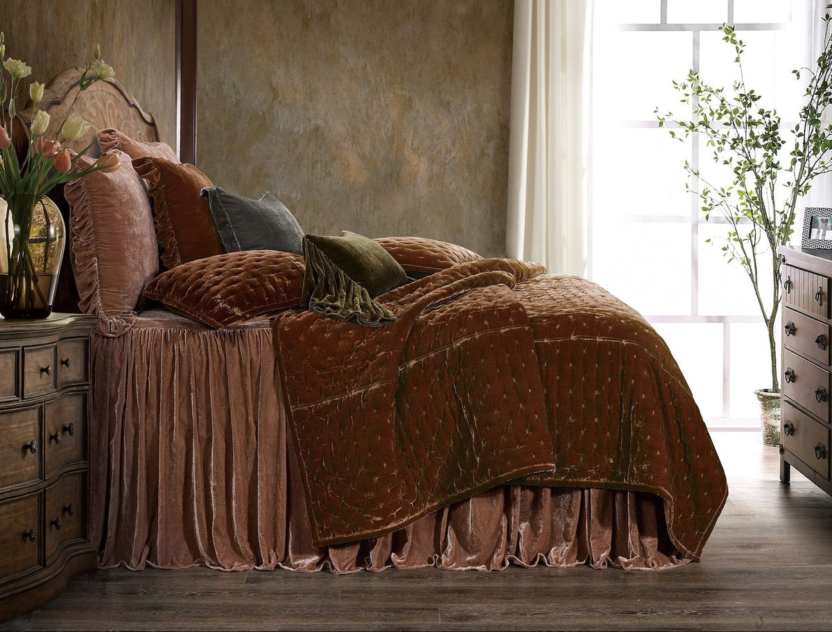 A copper Stella Pintuck quilt layered over a rose Stella velvet bedspread with ruffled shams and olive and slate velvet pillows