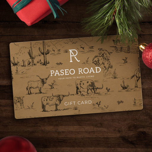 Rustic-themed gift card on wood surface, surrounded by festive holiday decorations.