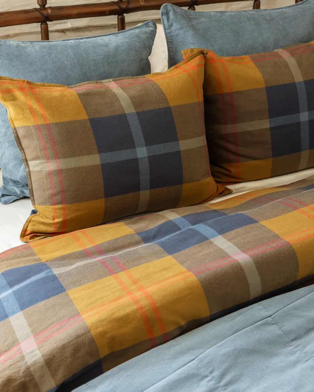 Pacific Plaid shams stacked against a light blue wide-wale corduroy pillow