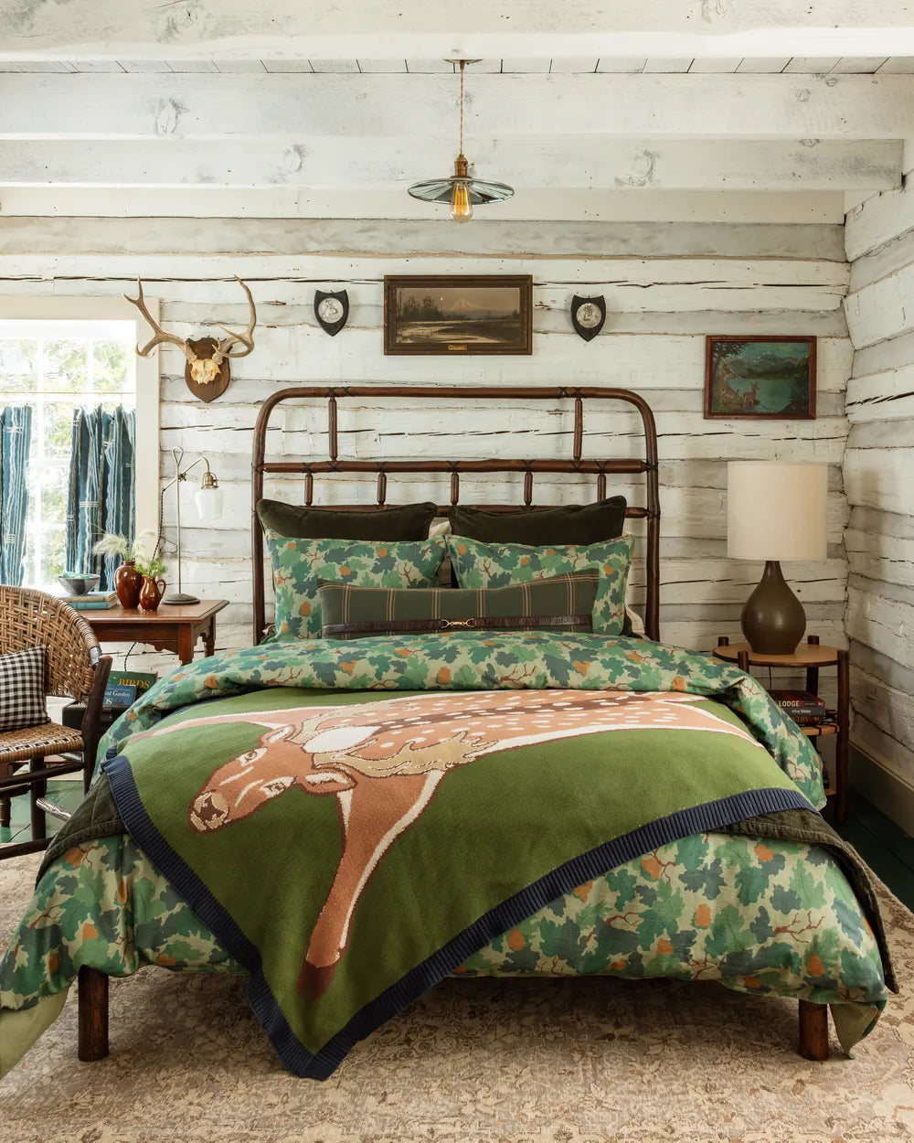 Oak leaf print bedding in moss and teal with a sweater-knit deer throw across the foot of a hickory bed