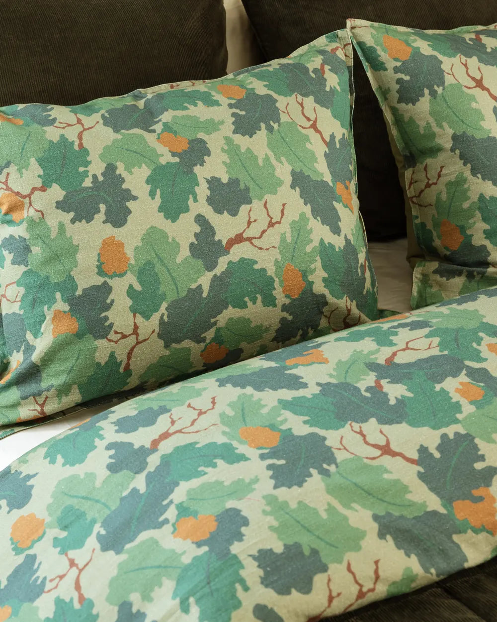Close view of the oak leaf print: moss and teal leaves with orange acorns on cream