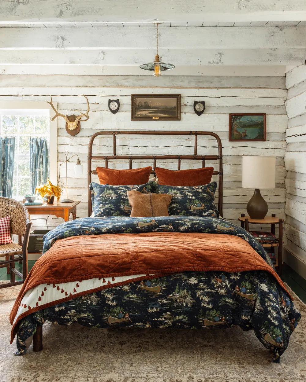 Camping Toile shams and duvet under a rust velvet coverlet with a tan corduroy pillow, on a hickory bed